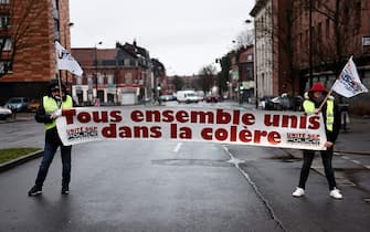 Police hold a banner that reads, ' All together united in anger' as they protest outside the police station of Roubaix, northern France on March 7, 2023, on the sixth day of nationwide rallies organized since the start of the year against French President's pension reform and its postponement of the legal retirement age from 62 to 64. - Massive strikes are expected from March 7, 2023, with promising unions to bring the country 