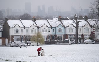 As March snow falls on south London, a boy builds a small snowman in front of period homes, in Ruskin Park, a public green space in Lambeth, on 8th March 2023, in London, England. (Photo by Richard Baker / In Pictures via Getty Images)