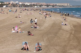 epa10520523 People sunbathe at Malvarrosa beach in Valencia, Spain, 13 March 2023. Temperatures will reach 30 degrees Celsius in Valencia on 13 March.  EPA/ANA ESCOBAR