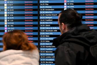 epa10519574 Passengers look at an electronic board showing canceled flights at the Berlin-Brandenburg airport, Germany, 13 March 2023. The employees of aviation security and ground handling services called for a 24 hours strike over wages.  EPA/FILIP SINGER