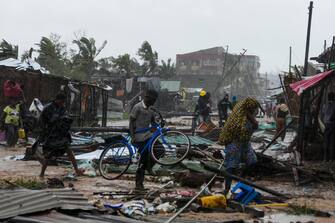 epa10517521 A man walks among the debris with his bycicle on a flooded street near Quelimane, as the storm Freddy hits Mozambique, 12 March 2023. The provincial capital of Quelimane will be the largest urban area closest to the cyclone's point of arrival on the mainland, and its radius (of about 300 kilometres) is expected to extend from Marromeu to Pebane, then moving inland towards Cherimane and southern Malawi. This is one of the longest lasting storms ever, after it formed at the beginning of February in the Asian seas, crossing the entire Indian Ocean to the east African coast.  EPA/ANDRE CATUEIRA
