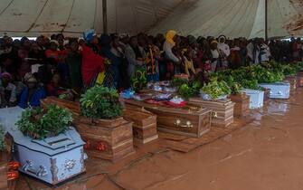 Mourners stand behind coffins of their relatives during a mass funeral for mudslide victims at Chilobwe townships Naotcha Primary school camp in Blantyre, Malawi, on March 15, 2023. - Malawi's president appealed on March 15, 2023 for global support to tackle "a national tragedy" after Cyclone Freddy slammed once again into the southeast African nation, causing flooding and mudslides that have killed hundreds. 
The storm returned to the African coast at the weekend for a second time in less than three weeks, leaving a trail of death and destruction. (Photo by Amos Gumulira / AFP) (Photo by AMOS GUMULIRA/AFP via Getty Images)