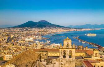 Scenic picture-postcard view of the city of Napoli (Naples) with famous Mount Vesuvius in the background in golden evening light at sunset, Campania,