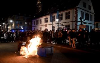 Protestors march next to a fire during a demonstration a few days after the government pushed a pensions reform through parliament without a vote, using the article 49,3 of the constitution in Strasbourg on March 20, 2023. - The French government survived two no-confidence motions in parliament on March 20, 2023 but still faces intense pressure over its handling of a controversial pensions reform. (Photo by Frederick FLORIN / AFP)