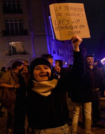 A protestor holds a placard that reads "Youth Rise Up! LRES= Republic is sweating (in reference of La Republique En March LREM party)" during a demonstration at Place Vauban, a few days after the government pushed a pensions reform through parliament without a vote, using the article 49,3 of the constitution in Paris on March 20, 2023. - The French government survived two no-confidence motions in parliament on March 20, 2023 but still faces intense pressure over its handling of a controversial pensions reform. (Photo by Christophe ARCHAMBAULT / AFP)