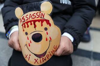A demonstrator holds a cardboard mask depicting Winnie-the-Pooh with the message 'Xi Jinping murderer' during a march of the Tibetan community in France in Paris on March 24, 2019 to protest against the visit of the Chinese President to France.  (Photo by KENZO TRIBOUILLARD / AFP) (Photo by KENZO TRIBOUILLARD/AFP via Getty Images)