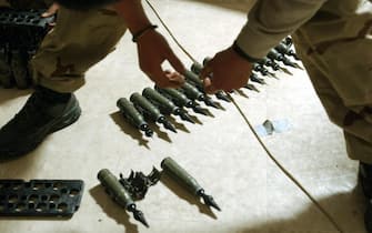 TIKRIT, IRAQ:  US Army Spcl. Sergio Cardenas of Charlie Company, from the 1-22 Battalion, 4th Infantry Division, stands over 25mm rounds of depleted uranium ammunition, 11 February 2004, at his base in Tikrit, 180 km (110 miles) north of Baghdad. The soldiers were taking inventory of the ammunition as they being to pack to leave for home in the US.  AFP PHOTO/Stan HONDA  (Photo credit should read STAN HONDA/AFP via Getty Images)