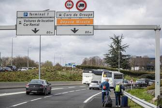 epa10538402 Passengers walk along a highway on their way to Paris CDG Airport during a Labour Unions operation that caused traffic disruption at the Terminal 1 amid a day of national strike led by French trade unions against the government's reform to the pension system, in Roissy, France, 23 March 2023. Protests continue in France after the prime minister announced on 16 March 2023 the use of Article 49 paragraph 3 (49.3) of the French Constitution to have the text on the controversial pension reform law - raising retirement age from 62 to 64 - be definitively adopted without a vote.  EPA/CHRISTOPHE PETIT TESSON