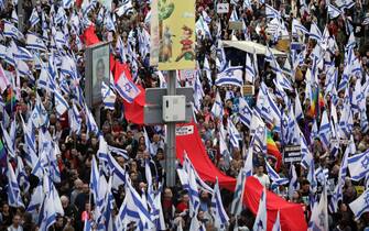 epa10543006 Protesters with Israeli flags during a mass protest against the government's justice system reform plans in Tel Aviv, Israel, 25 March 2023. Nationwide anti-government protests have been sparked by Israeli government plans to reform the justice system and limit the power of the Supreme Court.  EPA/ABIR SULTAN