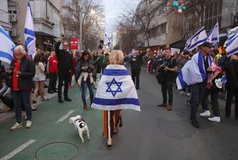 epa10542839 A protesters with Israeli national flag walks with her dog during a march against government's justice system reform plans in Tel Aviv, Israel, 25 March 2023. Nationwide anti-government protests have been sparked by Israeli government plans to reform the justice system and limit the power of the Supreme Court.  EPA/ABIR SULTAN