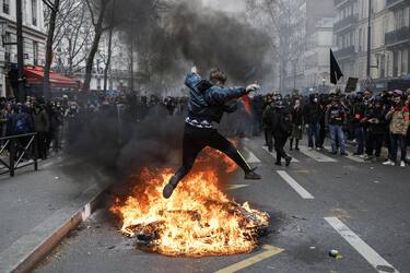 epa10547278 A protester jumps over a fire during a rally against the government's pension reform in Paris, France, 28 March 2023. France faces an ongoing national strike against the government's pensions reform after tthe French prime minister announced on 16 March 2023 the use of Article 49 paragraph 3 (49.3) of the French Constitution to have the text on the controversial pension reform law - raising retirement age from 62 to 64 - be definitively adopted without a vote.  EPA/CHRISTOPHE PETIT TESSON