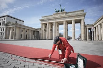 29 March 2023, Berlin: A man fastens the red carpet in front of the Brandenburg Gate ahead of British King Charles III's visit to Germany.  Before his coronation in May 2023, the British king and his royal wife will visit Germany for three days.  Photo: Michael Kappeler/dpa (Photo by Michael Kappeler/picture alliance via Getty Images)