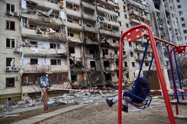 KYIV, UKRAINE - FEBRUARY 25: A child on a swing outside a residential building damaged by a missile on February 25, 2022 in Kyiv, Ukraine. Yesterday, Russia began a large-scale attack on Ukraine, with Russian troops invading the country from the north, east and south, accompanied by air strikes and shelling. The Ukrainian president said that at least 137 Ukrainian soldiers were killed by the end of the first day.  (Photo by Pierre Crom/Getty Images)