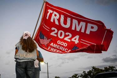 A supporter of former US President Donald Trump holds a "Trump 2024" flag as she protests near the Mar-a-Lago Club in Palm Beach, Florida, on March 30, 2023. - A New York grand jury has voted to indict former US president Donald Trump over hush money payments made to porn star Stormy Daniels ahead of the 2016 election, multiple US media reported on March 30, 2023. (Photo by CHANDAN KHANNA / AFP) (Photo by CHANDAN KHANNA/AFP via Getty Images)