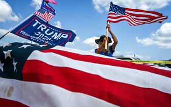 Lis Depiero, a supporter of former US President Donald Trump, holds a US flag near Mar-a-Lago in Palm Beach, Florida, on April 2, 2023. - Trump is expected to surrender to the authorities in New York on April 4, 2023 to face charges over a hush-money payment to porn star Stormy Daniels. (Photo by Giorgio Viera / AFP)