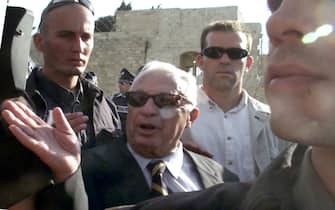 Israeli right-wing opposition leader Ariel Sharon (C) is flanked by security guards as he leaves the Al-Aqsa mosque compound in Jerusalem's Old City 28 September 2000. Some 29 people were hurt when Israeli police fired on stone-throwing Palestinian protesting Sharon's visit to Islam's third holiest shrine.  At least four Palestinians were hit by rubber bullets while 25 policemen were hurt by stones.  (Photo credit should read ANDRE DURAND/AFP via Getty Images)
