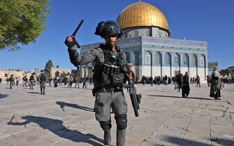 TOPSHOT - A member of the Israeli security forces lifts his batton in front of the Dome of the Rock mosque during clashes at Jerusalem's Al-Aqsa mosque compound, on April 15, 2022. - Witnesses said that Palestinian protestors threw stones at Israeli security forces, who fired rubber bullets at some of the demonstrators.  (Photo by AHMAD GHARABLI / AFP) (Photo by AHMAD GHARABLI/AFP via Getty Images)