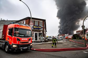 epa10566215 Firefighters try to extinguish a fire burning at a warehouse in the Rothenburgsort district of Hamburg, Germany, 09 April 2023. Residents have been warned of heavy smoke and possible toxins in the air. An alert issued by the Hamburg fire department said smoke gasses and chemical components in the air could affect breathing.  EPA/DOMINICK WALDECK