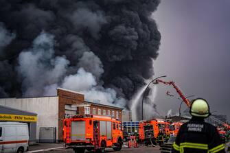 epa10566214 Firefighters try to extinguish a fire burning at a warehouse in the Rothenburgsort district of Hamburg, Germany, 09 April 2023. Residents have been warned of heavy smoke and possible toxins in the air. An alert issued by the Hamburg fire department said smoke gasses and chemical components in the air could affect breathing.  EPA/DOMINICK WALDECK