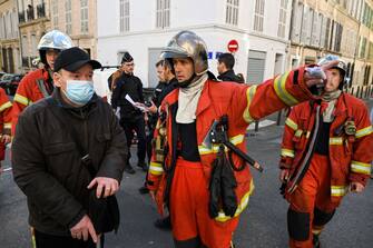 A firefighter gestures as inhabitants of the 'rue Trivoli' are evacuated after a building collapsed in the same street, in Marseille, southern France, on April 9, 2023. - 