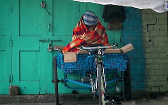 A homeless man sits on a cycle rickshaw parked along a street during a cold winter morning in New Delhi on January 4, 2023. (Photo by Money SHARMA / AFP) (Photo by MONEY SHARMA/AFP via Getty Images)