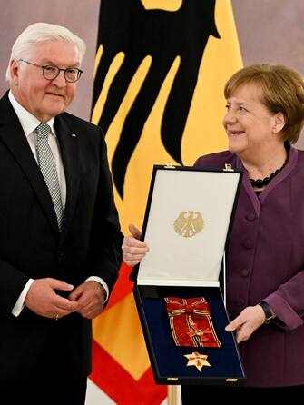 epa10577228 Former German Chancellor Angela Merkel (R) poses with the box after she was awarded the 'Grand Cross of the Order of Merit of the Federal Republic of Germany' by German President Frank-Walter Steinmeier (L) during a ceremony in Berlin, Germany , April 17, 2023. EPA/FILIP SINGER