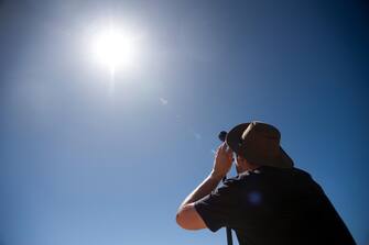 epa10581215 A person looks through a lens at the sun ahead of a total solar eclipse at a viewing site 24km from Exmouth, Western Australia, Australia, 20 April 2023. The total solar eclipse will occur on a remote peninsula on the Western Australian coast.  EPA/AARON BUNCH AUSTRALIA AND NEW ZEALAND OUT