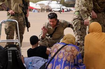 epa10594199 A handout photo made available by the British Ministry of Defence (MOD) of a Royal Marine checking on a child as they wait to board an aircraft for Cyprus, at Wadi Seidna Airport, near Khartoum, Sudan 27 April 2023. The UK has undertaken a military operation to evacuate British nationals from Sudan, due to escalating violence. The operation involved more than 1,200 personnel from 16 Air Assault Brigade, the Royal Marines and the Royal Air Force.  EPA/ARRON HOARE/BRITISH MINISTRY OF DEFENCE HANDOUT -- MANDATORY CREDIT: MOD/CROWN COPYRIGHT -- HANDOUT EDITORIAL USE ONLY/NO SALES