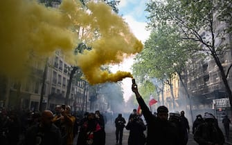 A protester brandishes a yellow smoke grenade as he takes part in a demonstration on May Day (Labour Day), to mark the international day of the workers, more than a month after the government pushed an unpopular pensions reform act through parliament, in Paris, on May 1, 2023. - Opposition parties and trade unions have urged protesters to maintain their three-month campaign against the law that will hike the retirement age to 64 from 62. (Photo by Alain JOCARD / AFP) (Photo by ALAIN JOCARD/AFP via Getty Images)