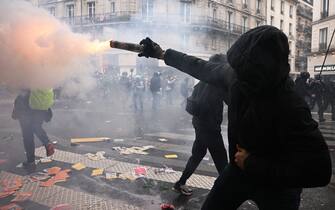 A protester shoots a firework during a demonstration on May Day (Labour Day), to mark the international day of the workers, more than a month after the government pushed an unpopular pensions reform act through parliament, in Paris, on May 1, 2023. - Opposition parties and trade unions have urged protesters to maintain their three-month campaign against the law that will hike the retirement age to 64 from 62. (Photo by Alain JOCARD / AFP) (Photo by ALAIN JOCARD/AFP via Getty Images)