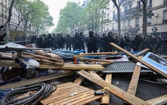 French Republican Security Corps (CRS - Compagnies Republicaines de Securite) police officers stand behind debris displayed by protesters during a demonstration on May Day (Labour Day), to mark the international day of the workers, more than a month after the government pushed an unpopular pensions reform act through parliament, in Paris, on May 1, 2023. - Opposition parties and trade unions have urged protesters to maintain their three-month campaign against the law that will hike the retirement age to 64 from 62. (Photo by Alain JOCARD / AFP) (Photo by ALAIN JOCARD/AFP via Getty Images)