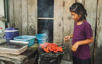Life and childhood in Asia.  Tasty and delicious meal made on the grill.  Traditional food of people in Asian village