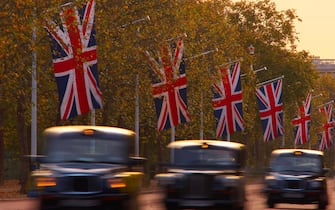 A blurred view of black London taxi cabs driving along The Mall at dusk.