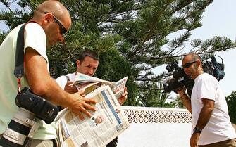 Reporters and photographers read the newspapers as they wait outside the rented villa of Kate and Gerry, parents of missing four-year-old Briton Madeleine McCann, in Praia da Luz, in southern Portugal 09 August 2007. Portuguese and British newspapers report that during a review of evidence sniffer dogs from the British police found traces of blood and the odor of a corpse inside the room from which Maddie went missing in May.  Madeleine McCann by this weekend will have been missing for 100 days from a hotel room in the southern Portuguese resort where she and her two-year-old twin siblings were sleeping while her parents were dining at a nearby restaurant.  AFP PHOTO / POOL/ STEVE PASRONS (Photo credit should read Steve Parsons/AFP via Getty Images)