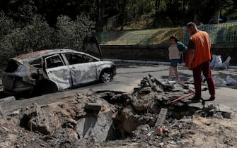 epaselect epa10662891 Two persons stand near a shell hole after debris fell outside an apartment building in a drone strike in Kyiv (Kiev), Ukraine, 30 May 2023, amid the Russian invasion. At least one person died and seven others injured after a Russian strike against the the Ukrainian capital, the Kyiv City Military Administration said on telegram. On 30 May Russian forces launched 31 'kamikaze' drones on Ukraine, 29 of which were shot down, said the Air Force Command of the Armed Forces of Ukraine. Russian troops entered Ukrainian territory in February 2022, starting a conflict that has provoked destruction and a humanitarian crisis.  EPA/SERGEY DOLZHENKO