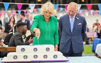 LONDON, ENGLAND - JUNE 05: Prince Charles, Prince of Wales watches as Camilla, Duchess of Cornwall cuts a cake at the Big Jubilee Lunch At The Oval on June 05, 2022 in London, England. The Platinum Jubilee of Elizabeth II is being celebrated from June 2 to June 5, 2022, in the UK and Commonwealth to mark the 70th anniversary of the accession of Queen Elizabeth II on 6 February 1952.  (Photo by Samir Hussein/WireImage)