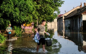 epaselect epa10676352 A boy carries his belongings as he evacuates from his home in a flooded street of Kherson, Ukraine, 06 June 2023.  Ukraine has accused Russian forces of destroying a critical dam and hydroelectric power plant on the Dnipro River in the Kherson region along the front line in southern Ukraine on 06 June. A number of settlements were completely or partially flooded, Kherson region governor Oleksandr Prokudin said on telegram. Russian troops entered Ukraine on 24 February 2022 starting a conflict that has provoked destruction and a humanitarian crisis.  EPA/IVAN ANTYPENKO