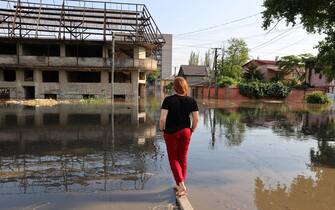 A woman looks at a flooded street in the town of Kherson, following flooding caused by damage sustained at the Kakhovka HPP dam, on June 6, 2023. The partial destruction on June 6, of the major Russian-held dam in southern Ukraine unleashed a torrent of water that flooded two dozen villages forcing mass evacuations, sparking fears of a humanitarian disaster near the war's front line. Moscow and Kyiv traded blame for ripping a gaping hole in the Kakhovka dam as expectations built over the start of Ukraine's long-awaited offensive. (Photo by STRINGER / AFP) (Photo by STRINGER/AFP via Getty Images)
