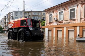 Rescuers ride an all-terrain vehicle during an evacuation from a flooded area in Kherson on June 8, 2023, following damages sustained at Kakhovka hydroelectric power plant dam. Ukrainian President Volodymyr Zelensky visited the region flooded by the breached Kakhovka dam Thursday, as the regional governor said 600 square kilometres were underwater. (Photo by ALEKSEY FILIPPOV / AFP)