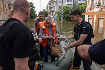 Ukrainian security forces help to unload local residents from a boat during an evacuation from a flooded area in Kherson on June 8, 2023, following damages sustained at Kakhovka hydroelectric power plant dam. Ukrainian President Volodymyr Zelensky visited the region flooded by the breached Kakhovka dam on June 8, 2023, as the regional governor said 600 square kilometres were underwater. (Photo by ALEKSEY FILIPPOV / AFP)