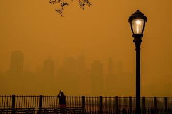 TOPSHOT - A person takes photos of the skyline as smoke from wildfires in Canada cause hazy conditions in New York City on June 7, 2023. An orange-tinged smog caused by Canada's wildfires shrouded New York on Wednesday, obscuring its famous skyscrapers and causing residents to don face masks, as cities along the US East Coast issued air quality alerts. (Photo by ANGELA WEISS / AFP)