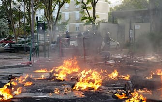 TOPSHOT - Police in riot gear stand next to a fire burning in the street  after a demonstration in Nanterre, west of Paris, on June 27, 2023, after French police killed a teenager who refused to stop for a traffic check in the city. The 17-year-old was in the Paris suburb early on June 27 when police shot him dead after he broke road rules and failed to stop, prosecutors said. The event has prompted expressions of shock and questions over the readiness of security forces to pull the trigger. (Photo by Zakaria ABDELKAFI / AFP) (Photo by ZAKARIA ABDELKAFI/AFP via Getty Images)