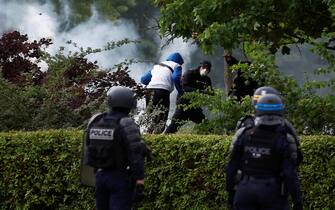 epa10717838 Protesters throw rocks during clashes with French riot police following a march in the memory of 17-year-old Nahel, who was killed by French Police in Nanterre, near Paris, France, 29 June 2023. Violence broke out after the police fatally shot a 17-year-old during a traffic stop in the Paris suburb of Nanterre on 27 June. France's interior minister said 40,000 police officers will be deployed on 29 June to prevent further outbreaks of violence on the third night of unrest.  EPA/YOAN VALAT