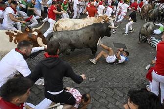 PAMPLONA, SPAIN - JULY 08: People take part in the traditional 'encierro' (bull-run) of the San Fermin Festival in Pamplona, Spain on July 08, 2023. The bull-running fiesta is held annually from 06 to 14 July in commemoration of the city's patron saint. Visitors from all over the world attend the festival. Many of them physically participate in the highlight event - the running of the bulls, or encierro - where they attempt to outrun the animals along a route through the narrow streets of Pamplona's old city. (Photo by Burak Akbulut/Anadolu Agency via Getty Images)