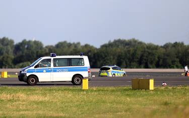 epa10743083 A police car drives on the runway as Letzte Generation (Last Generation) climate activists protest at the airport in Duesseldorf, Germany, 13 July 2023. According to the climate activists, they blocked the runways of the airports in Duesseldorf and Hamburg to protest against the government's lack of plan and breach of the law in the climate crisis.  EPA/FRIEDEMANN VOGEL
