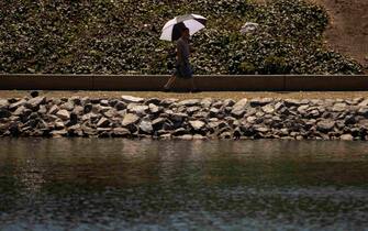 epa10748614 A man uses an umbrella to protect himself from the sun during a heatwave at Echo Park in Los Angeles, California, USA, 15 July 2023. More than a third of Americans are under extreme heat warnings or advisories with records expected to be broken in several cities across the Southern and Western US according to the National Weather Service.  EPA/ETIENNE LAURENT