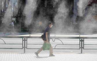 epa10738836 A passerby walks past a mist spray on a hot day in Tokyo, Japan, 11 July 2023. According to preliminary data by the World Meteorological Organization, the first week of July was the hottest week on record.  EPA/FRANCK ROBICHON