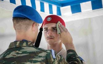 epaselect epa10745424 An officer wipes the face of a Greek Presidential guard as he performs his duties in front of the parliament building during an extreme heatwave, in Athens, Greece, 14 July 2023. Anticyclone Ceber, a high-pressure area coming from the south, will bring extreme heat with temperatures exceeding 40 degrees Celsius to European countries, as well as China and the USA, the European Space Agency (ESA) reported.  EPA/KOSTAS TSIRONIS