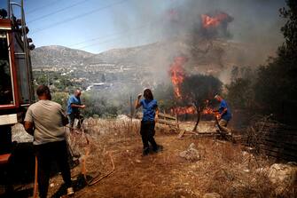 epa10751577 Local firefighters operate during a wildfire at Kouvaras area in Attica, Greece, 17 July 2023. Firefighting forces are battling a blaze that broke out in the Kouvaras area in Attica, while a warning was sent via the emergency number 112 to evacuate several settlements in southeast Attica. A force of 55 firefighters and 20 fire engines, two units on foot and 31 Romanian firefighters with five water tankers have been deployed to put out the fire, assisted by six fire-fighting aircraft and four helicopters from the air.  EPA/YANNIS KOLESIDIS