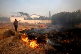 epa10751680 A man battles a wildfire raging at Lagonisi area, Greece, 17 July 2023. Firefighting forces are battling a blaze that broke out in the Kouvaras area in Attica, while a warning was sent via the emergency number 112 to evacuate several settlements in southeast Attica. A force of 55 firefighters and 20 fire engines, two units on foot and 31 Romanian firefighters with five water tankers have been deployed to put out the fire, assisted by six fire-fighting aircraft and four helicopters from the air.  EPA/YANNIS KOLESIDIS